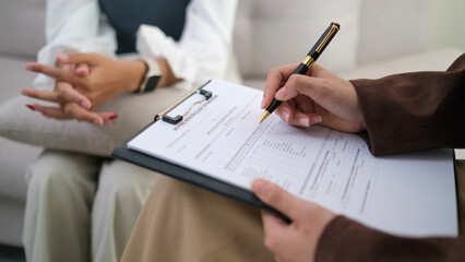 Professional psychotherapist  with clipboard listening attentively to her patient during therapy Session. Advice, assistance and mental health concept.