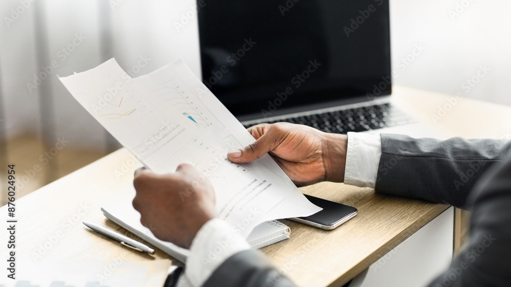Aufkleber a businessman sits at a desk, carefully reviewing a document with graphs and charts.