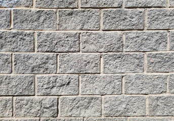 Granite  surface texture, background. The wall is made of gray stone blocks.