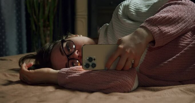 Upset, sad teenage girl in glasses using smartphone, put it away with disappointment, frustration and fatigue. Smartphone depression concept. Tired and bored teen girl