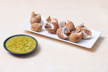 Fresh sea babylonia areolata shell boiled on the white dish. Served with spicy seafood sauce.