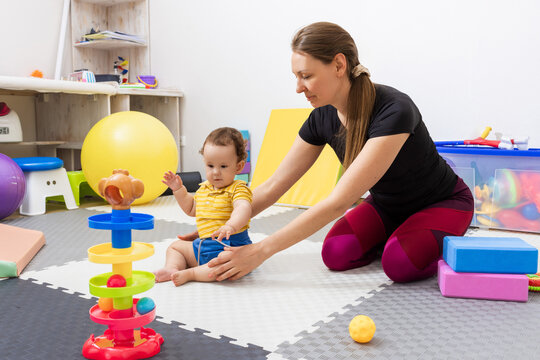 Physiotherapist assisting a little child with coordination disorders during motor skills development exercise in modern rehab clinic. Physiotherapy