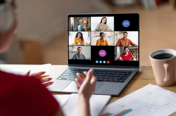 A woman sits at her desk, participating in a video conference call on her laptop. The screen...