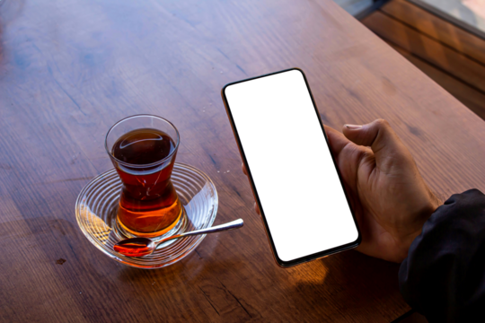 Hand holding blank screen smartphone at the cafe with Turkish tea,, mockup phone, transparent background png