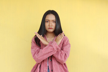 Fototapeta premium Beautiful Asian girl smiling and looking camera wear pink jacket on yellow background.