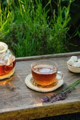 Lavender tea in a transparent teapot served on a wooden tray in the garden. Drinks with lavender.