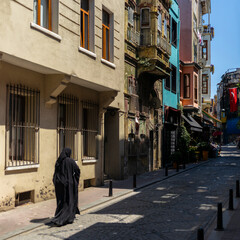 An unrecognizable Turkish woman in the full cover black dress in the narrow streets in the Balat...
