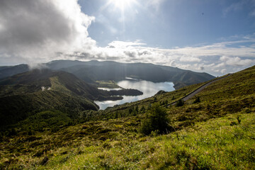 Fototapeta premium Miradouro do Lagoa do Fogo, Azores, Ponta Delgada, Isla Sao Miguel. Scenic landscape in trekking friendly path over cloudy mountains and green landscape scenario. Azores and trekking travel tourism