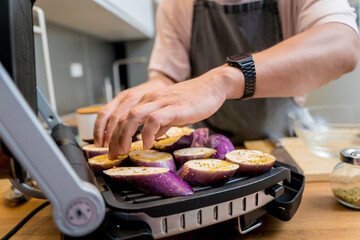 Chef at the kitchen preparing grilled eggplants with garlic