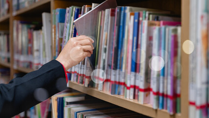Woman read book, studying, research, school, education concept. A businesswoman person is reaching for a book on a library shelf.