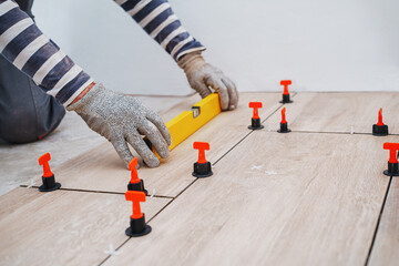 Laying tiles concept with close up hands. Tiler, spatula and glue when laying tiles. Pull tabs and...