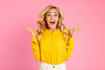 A young woman with blonde hair is standing in front of a pink background. She is wearing a yellow button-down shirt and white pants