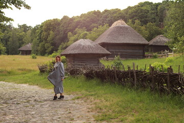 Young brunette woman in vintage dress walking in a countryside by the brick road