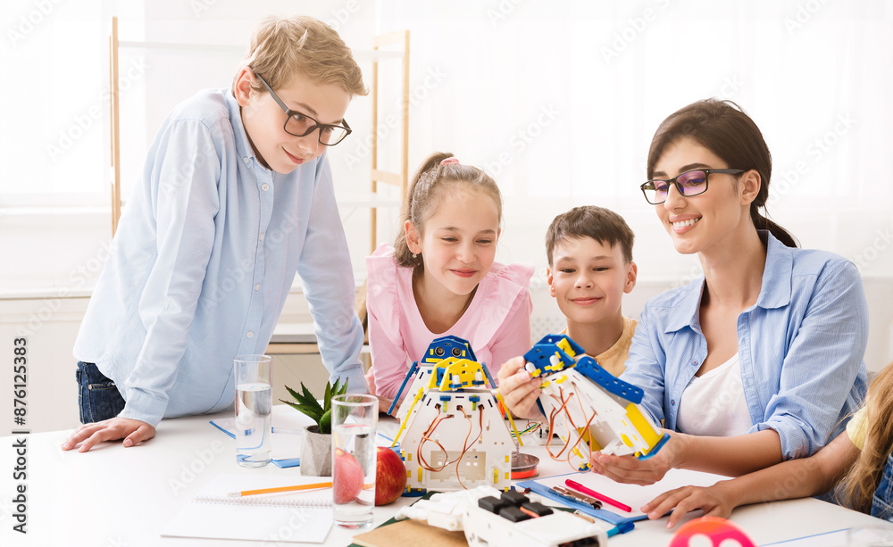 Poster A teacher is helping her students build robots during a classroom activity. They are smiling and working together on the project. Positive and engaging learning environment for STEM education.
