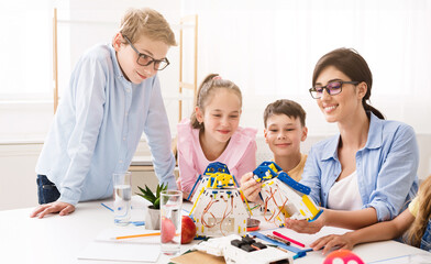 A teacher is helping her students build robots during a classroom activity. They are smiling and working together on the project. Positive and engaging learning environment for STEM education.