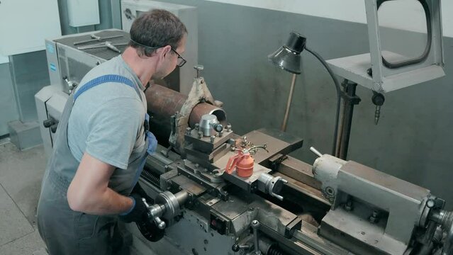 A machinist operates a lathe machine on a large metal pipe inside an industrial workshop, demonstrating the essential processes and precision needed for mechanical fabrication and component shaping.