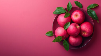 Red apples with green leaves in a bowl on a pink background with copy space, creating a fresh and modern display, perfect for healthy food promotions