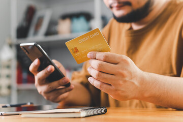 Close up Male hands holding credit card and smartphone, man paying online, credit card shopping, using banking service, entering information, shopping, ordering in internet store, doing secure payment