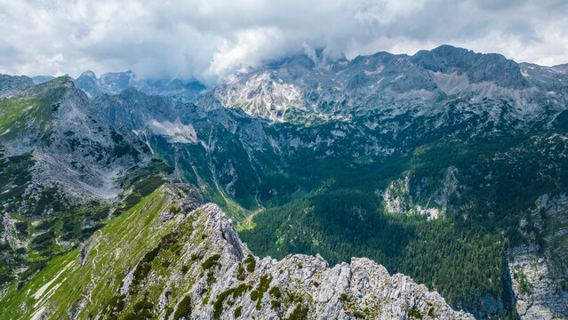 An awe-inspiring aerial view of the Slovenian Alps, featuring the majestic peaks of Vi&scaron;evnik, Jezerca, and Veliki Dra&scaron;ki vrh. These stunning mountains offer breathtaking hiking trails