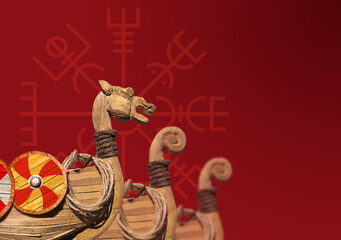 three prows of a Viking warship, one with dragon's head on a red background against a rune © sharpner