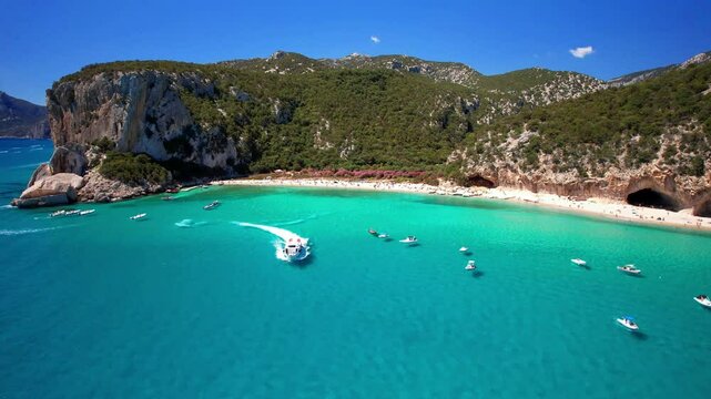 Aerial 4K Drone Follow Shot of a Motorboat Speeding Through Turquoise Water in Cala Luna Beach and Caves in Sardegna (Sardinia) Italy