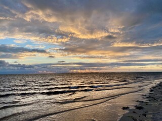 Sonnenuntergang am Strand von Utersum auf der Insel Föhr im Wattenmeer der Nordsee mit Blick zu den Leuchturm der Insel Amrum und Wiek