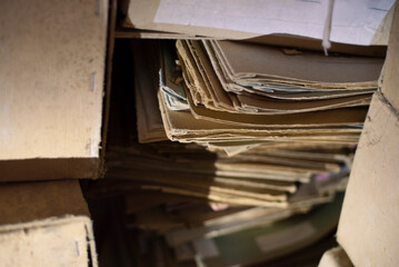 Old paper archives lie in a dark room, in an abandoned room. Old folders, old forms of the last century, selective focus