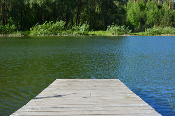 a wooden dock that has a green lake in the background