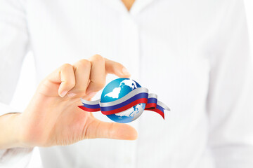 A hand holding a globe with a red ribbon around it. Russia flag world shape and businesswoman