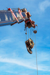 The construction crane with hook over cloud and blue sky background at construction site