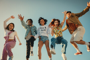 Group of friends joyfully posing and jumping in summer sky