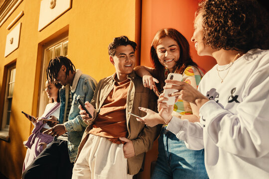 Group of happy friends sharing moments and fun with smartphones outdoors