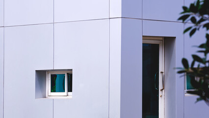 Gray aluminium composite tile wall of modern security guardhouse in front of gated community, perspective side view