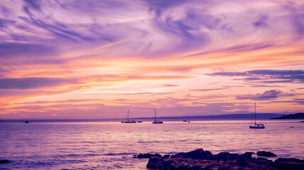 Fototapeta premium Literal description of the image: Sailing boats on the ocean at sunset with purple and orange sky.