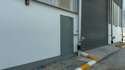 Exterior view of the steel fire exit door and pvc downspout and roller shutter door.
