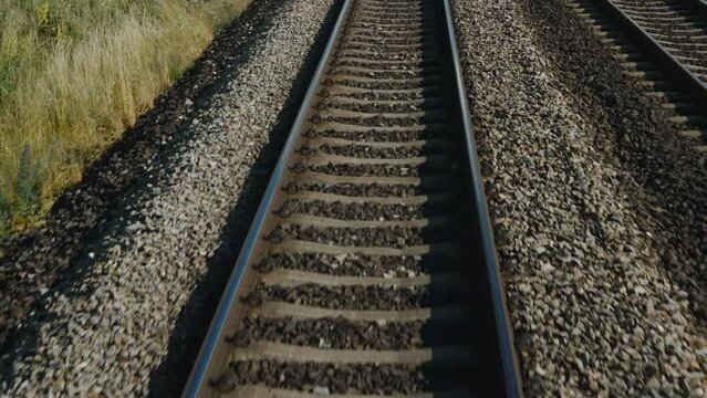 Background of fast forward movement on rails with crushed stone, point of view from the train driver.. High-speed rail transportation. Railway infrastructure tracks.