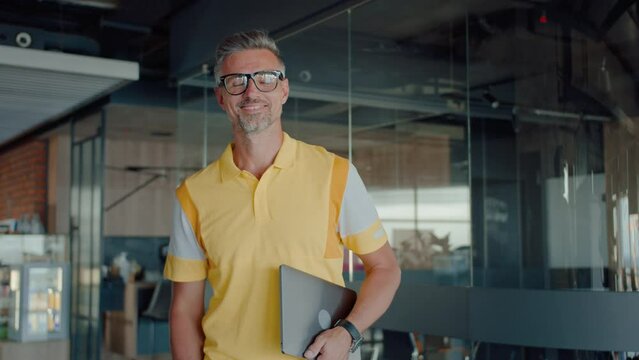 Mature male in yellow polo shirt in modern office interior