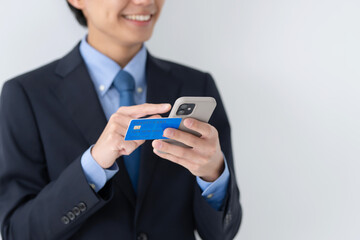 クレジットカードとスマートフォンを使うビジネス男性