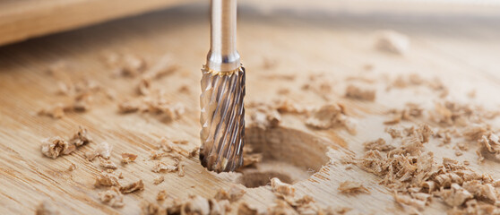 end mill makes a hole in the wooden oak table with wood