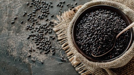 Black rice in bowl with spoon on sack