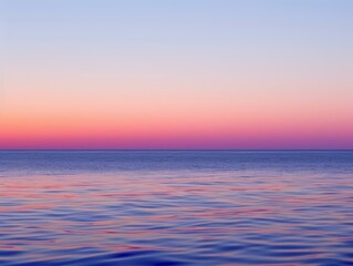 Obraz premium A serene scene of the ocean at sunset, with calm waters reflecting the vibrant pink and purple hues of the sky