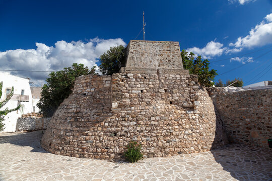 Stone fortification in Kastro district in Antiparos island, Greece, showcasing the island's rich history and architectural heritage under a blue sky with white clouds.
