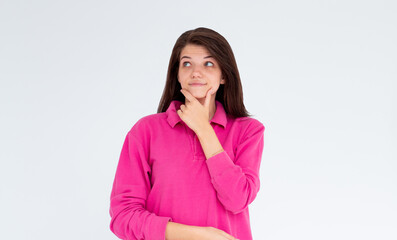 Fototapeta premium Thoughtful woman keeps hand on chin looks pensively above dressed in casual pink sweatshirt poses against white background blank copy space for your advertising content thinks about future