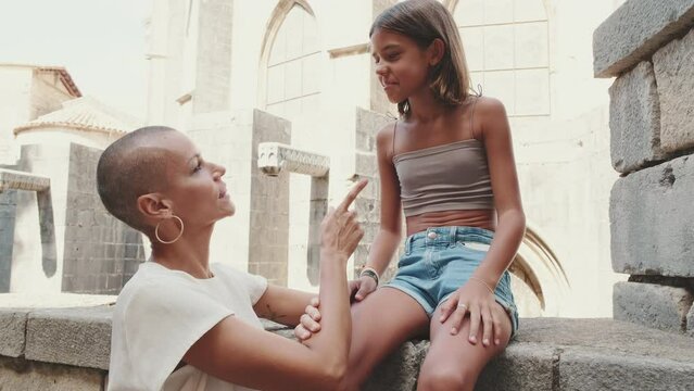 A mother talks to her daughter against the backdrop of a historic building in the city center 