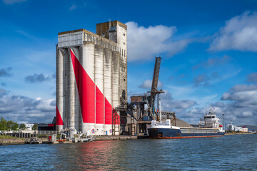 Cargo carrying cereal grain in the port of Saint Nazaire in France, in front of the grain silos © sissoupitch