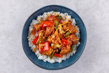 Rice with pork and vegetables in a sweet and sour sauce on a grey background, for a restaurant menu or food delivery