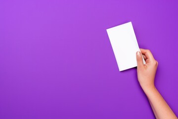 Obraz premium A hand reaches out to hold a blank white sheet of paper against a vibrant purple background