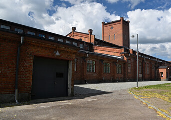 A historic brick industrial building with large arched windows and a prominent tower