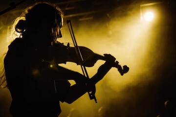 Fototapeta premium A silhouetted violinist performs on stage under the warm glow of stage lights, their passion and dedication visible in their focused posture