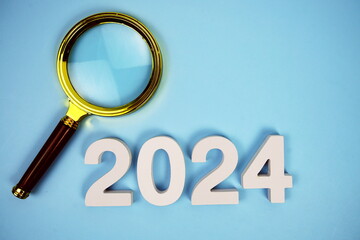 Happy New Year 2024 and magnifying glass top view on blue background, new year goal and resolution concept background